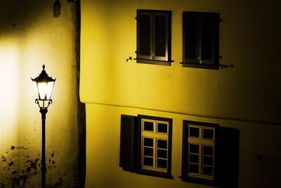 Illuminated street light against yellow building