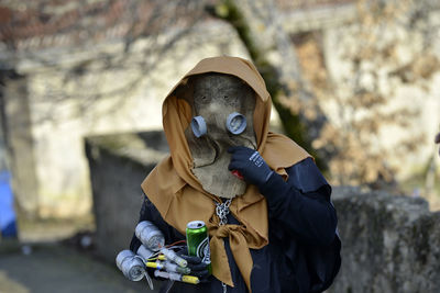 Person wearing costume while holding equipment and drinking can