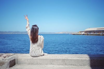 Rear view of woman on beach against clear sky