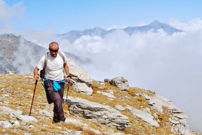 Mature man hiking on mountain against sky