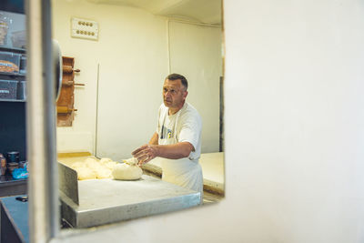 Man weighing dough on a scale at a pasta shop in belgrade, serbia