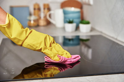 Woman in rubber gloves cleaning induction stove