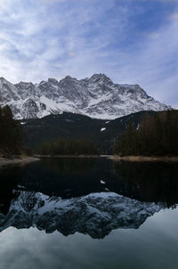 Scenic view of lake by snowcapped mountains against sky