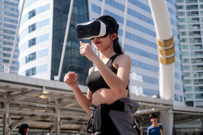 Low angle view of woman using virtual reality simulator in city