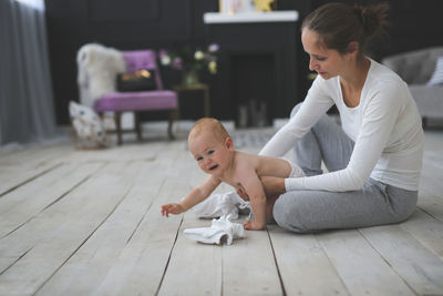 Side view of young woman sitting on hardwood floor