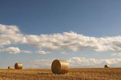 Hay bales on field against sky