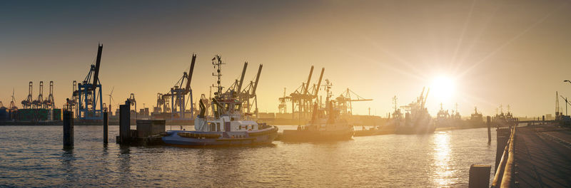 Sailboats in harbor against sky during sunset