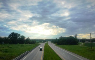 View of country road against cloudy sky
