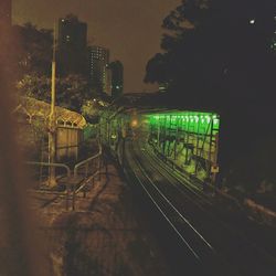 Train on illuminated railroad tracks against sky at night