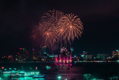 Firework display in city against sky at night