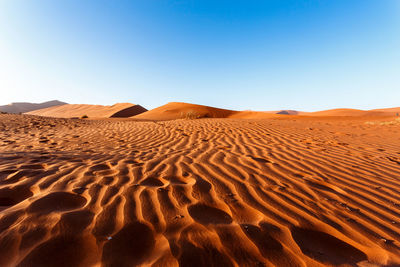 Sand dunes in desert against clear sky