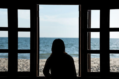 Rear view of silhouette man looking at sea against sky