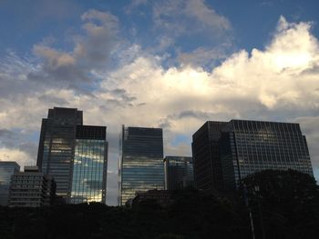Low angle view of modern building against cloudy sky