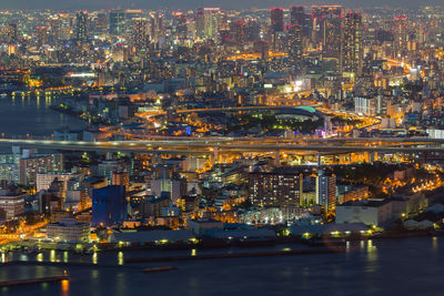 Illuminated city by river at night