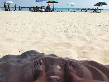 Low section of person relaxing on sand at beach