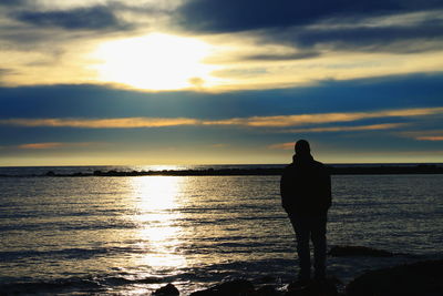 Silhouette man standing on beach against sky during sunset