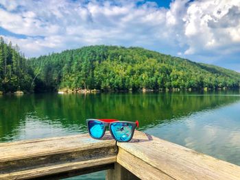 Boat on lake by trees against sky