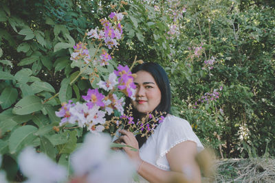 Portrait of beautiful young woman by flowering plants