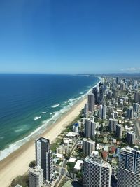 High angle view of sea and buildings against clear blue sky