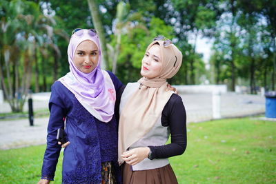 Young woman with arms raised standing against plants