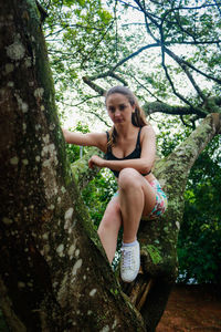 Low angle view of young woman on tree