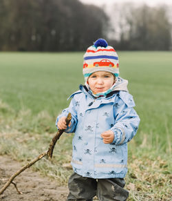Boy in warm clothing standing on field