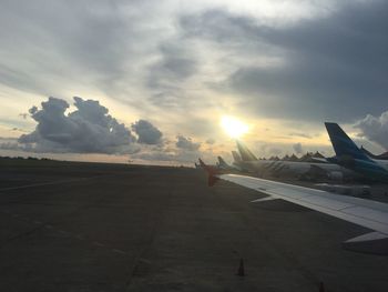 Airplane on runway against sky during sunset