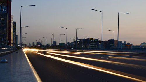 Light trails on highway in city against sky