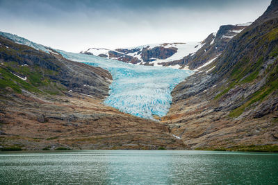 Scenic view of lake by mountains against sky