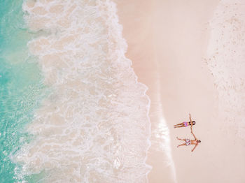 Aerial view of couple relaxing on sandy beach