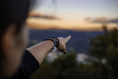 Midsection of man holding cat against sky during sunset