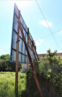 Low angle view of rusty metallic structure on field against sky