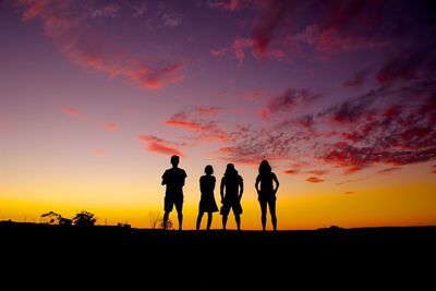 Silhouette people on landscape against sky during sunset