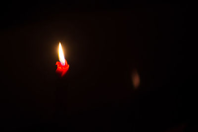 Close-up of lit candle in darkroom