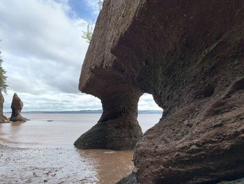 Rock formation on beach against sky