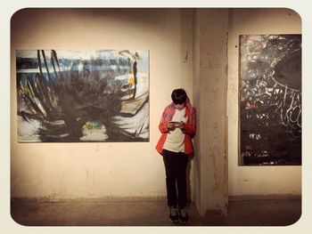 Young woman standing against wall