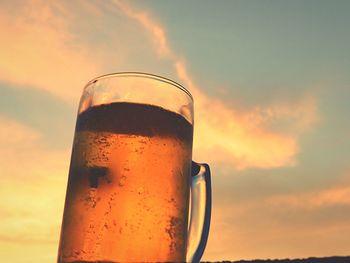 Low angle view of beer glass against sunset sky