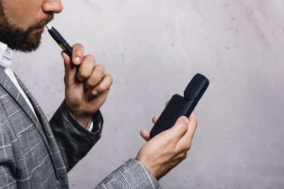 Midsection of man smoking electronic cigarette