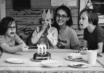 Smiling friends celebrating birthday on table at home