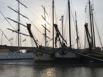 Sailboats moored in sea against sky