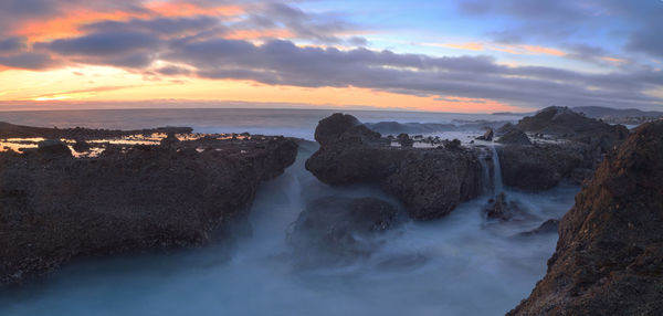 Scenic view of sea against cloudy sky during sunset