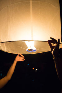 Midsection of person holding illuminated lamp in dark room