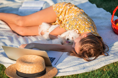 High angle view of girl lying down with dog outdoors