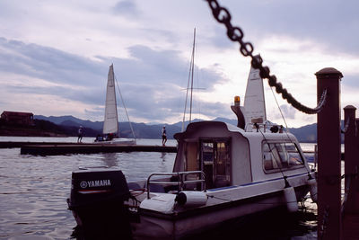 Sailboats moored at harbor against sky