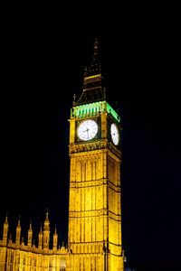 Low angle view of clock tower at night