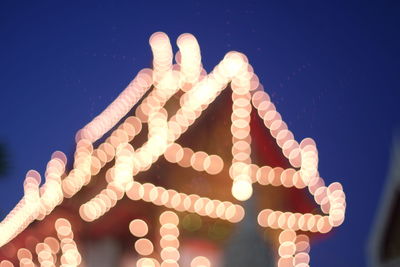 Low angle view of illuminated text against sky at night