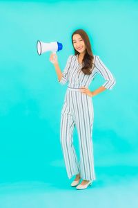 Portrait of smiling woman standing against blue background