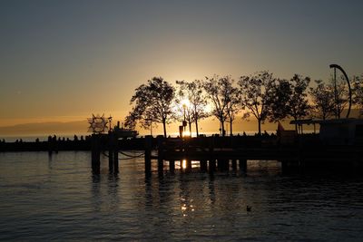 Silhouette trees by lake against sky during sunset