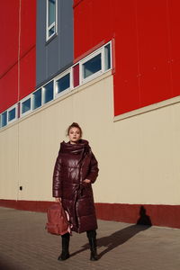 Full length portrait of teenage girl standing against wall