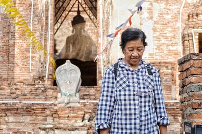 Senior woman standing against old temple